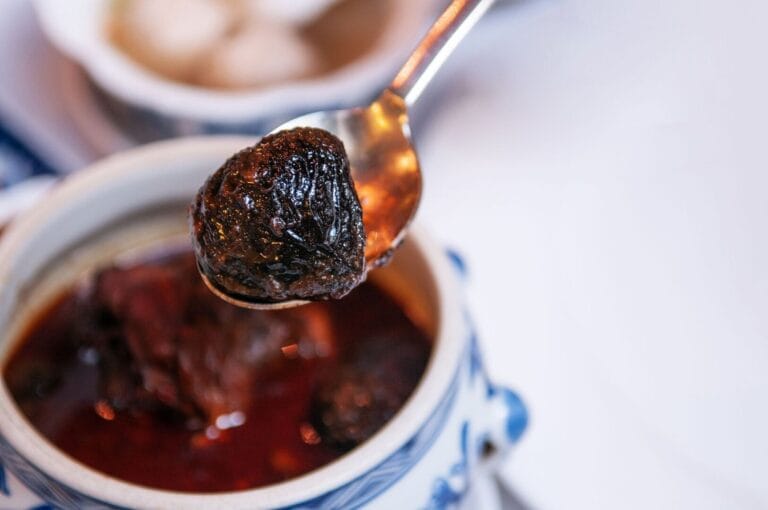A spoonful of Peranakan food in a bowl, accompanied by a spoon resting beside it.