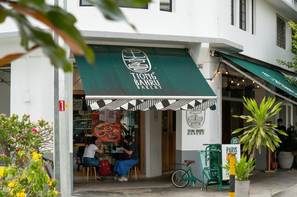 A green awning shades a cafe in Tiong Bahru, with patrons enjoying their time seated outside.