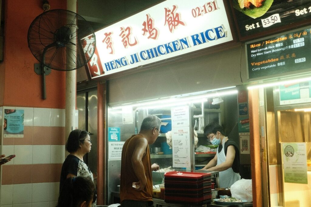 A vibrant Singaporean hawker stall specializing in chicken rice, showcasing a variety of dishes and a bustling atmosphere.