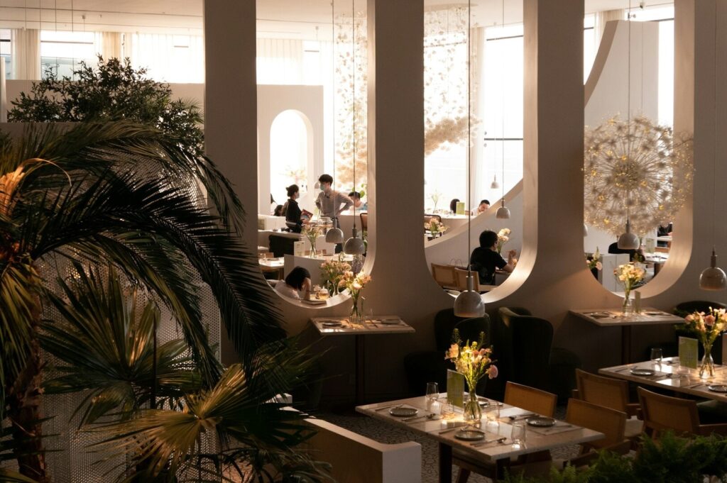 A lively Singapore restaurant adorned with numerous plants, featuring diners engaged in conversation and enjoying their meals.