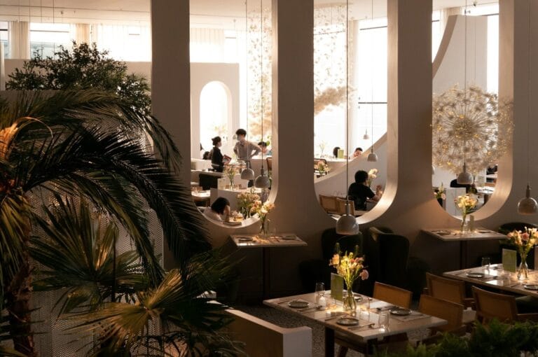 A lively Singapore restaurant adorned with numerous plants, featuring diners engaged in conversation and enjoying their meals.