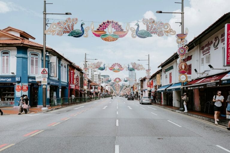 A vibrant street in Little India, Singapore, adorned with colorful decorations and bustling with people walking.