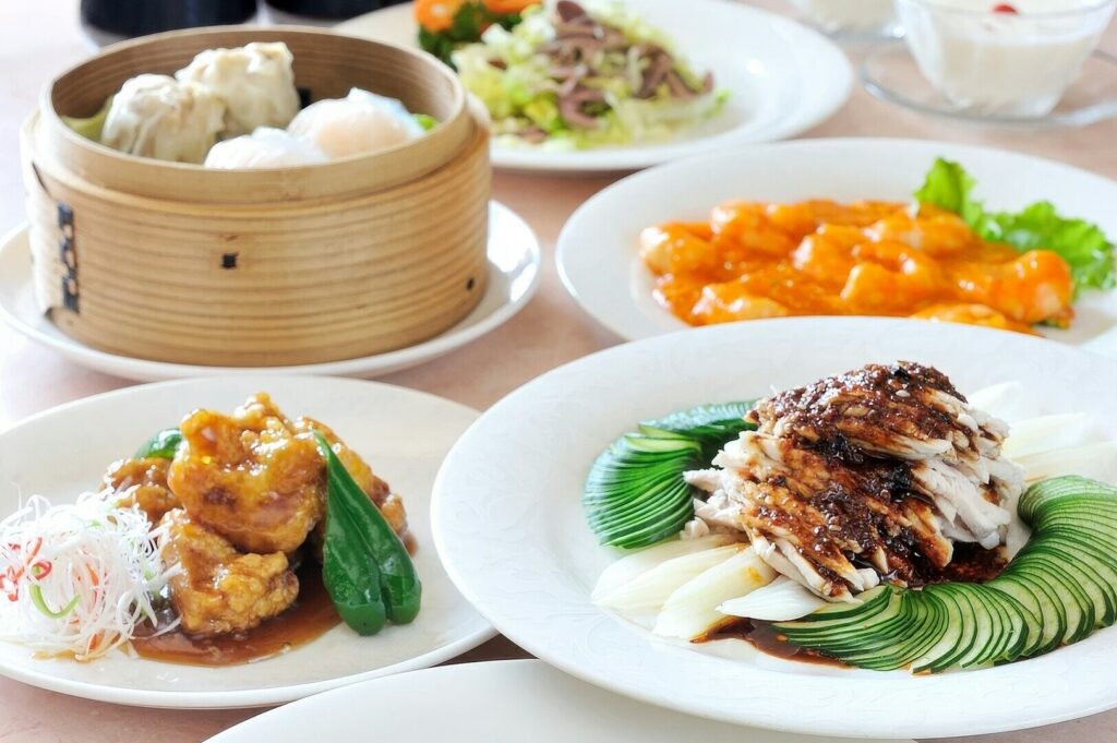 A table set with plates of chicken, vegetables, and rice, showcasing premier dining in Singapore.