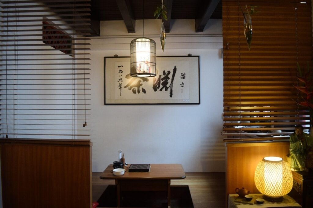 Interior of Tea Chapter on Neil Road, showcasing wooden blinds and a table in a serene setting.