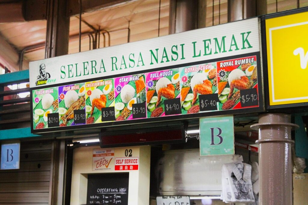 Storefront with a sign reading "Selera Rasa Nasi Lemak." Menu images show rice meals with sides like fish and chicken. Prices range from $2.90 to $5.90.