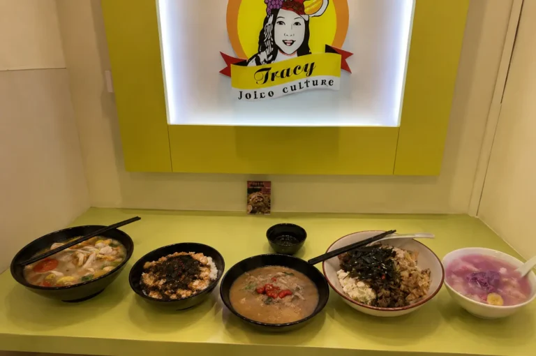 Row of vegetarian soups and rice bowls on a green counter below the Tracy Joico culture sign