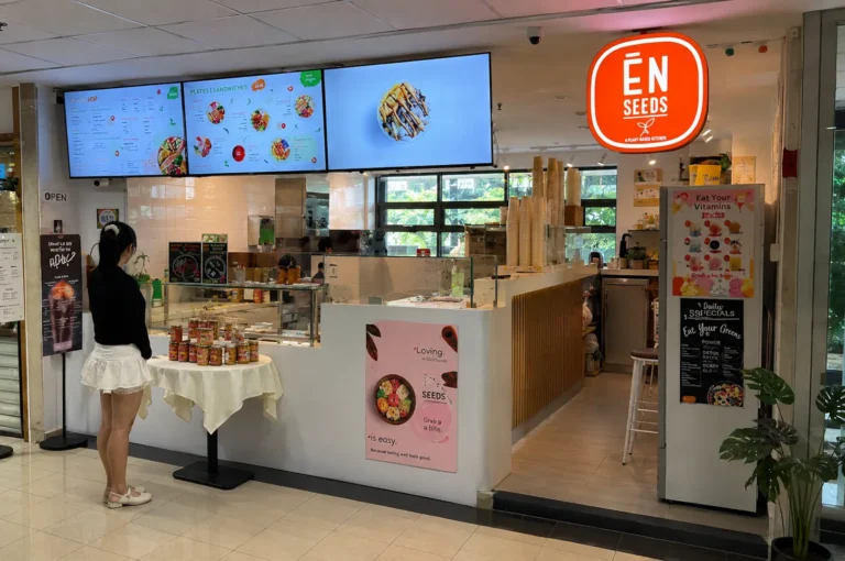En Seeds plant-based kitchen storefront with digital menu screens and a customer browsing