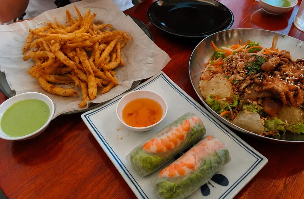 Asian food spread with fried snacks, fresh spring rolls, and seafood salad dishes