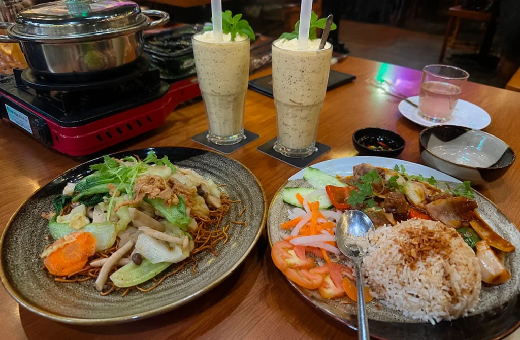 Asian restaurant meal with fried noodles, rice dish, and blended drinks on a table