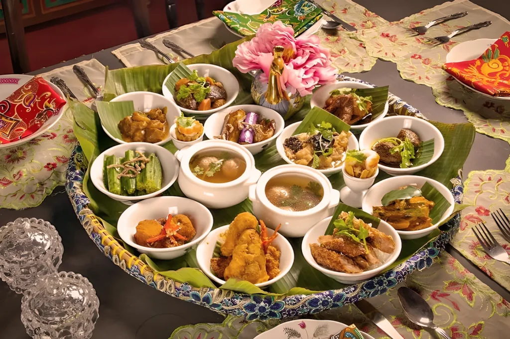A vibrant Thai meal presentation on a large tray with banana leaves, featuring various colorful dishes, soups, and garnished with a pink flower centerpiece.