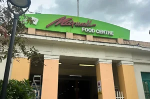 Exterior entrance of the historic Maxwell Food Centre in Singapore, showing the prominent green signage above the pillars.