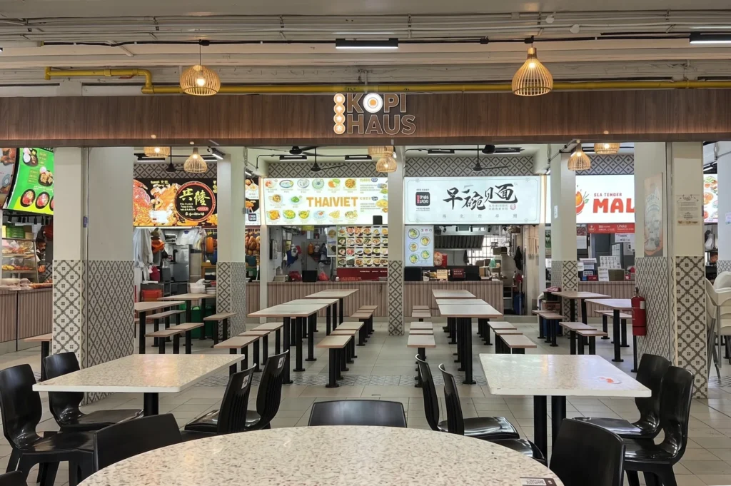 Wide shot of the Kopi Haus food court interior with clean seating areas and various food stalls like ThaiViet.