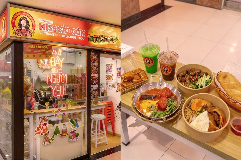 A small, vibrant Vietnamese food stall named "Miss Sài Gòn" with colorful decorations. On the right, various dishes displayed on a table, including rice bowls, a skillet dish, bread, and two beverages in takeaway cups. The scene conveys a welcoming and appetizing atmosphere.