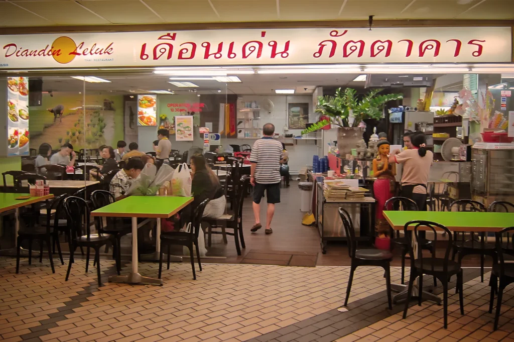 Diandin Leluk Thai Restaurant storefront at Golden Mile Complex, featuring its iconic yellow logo and a bustling dining area filled with customers.