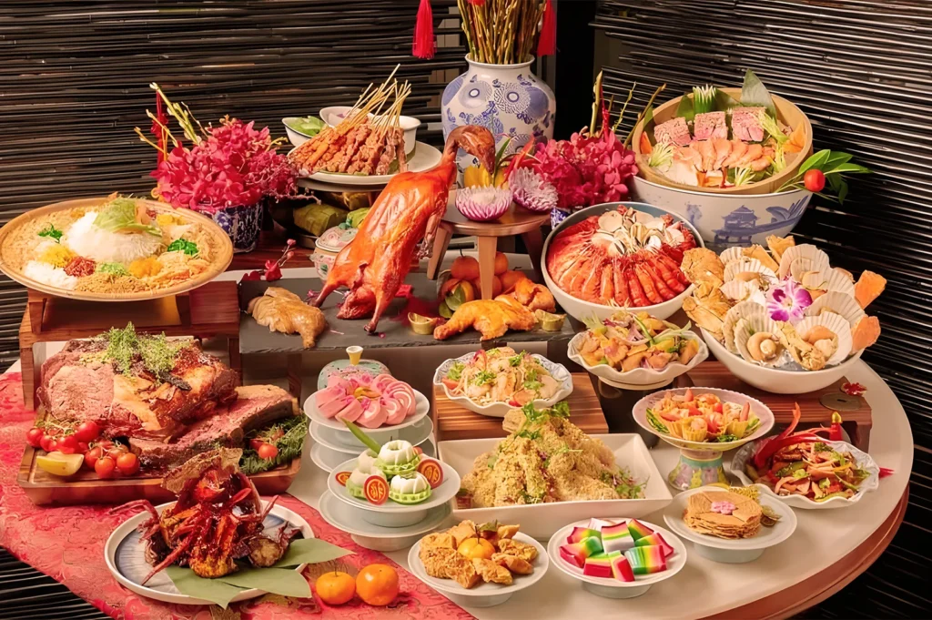 A lavish spread of Asian cuisine on a table, featuring roasted duck, sushi, seafood, and colorful desserts. The setting is festive with floral decor.