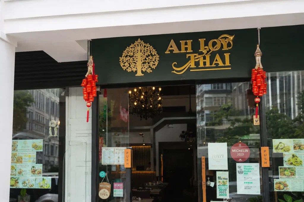 Ah Loy Thai restaurant storefront with green and gold signage, red festive decorations, and a Michelin 2023 sticker