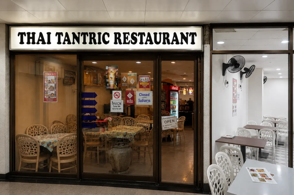 Thai Tantric Restaurant storefront with illuminated sign and diners at tables