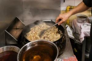 Chef stir-frying fried rice in a steaming wok