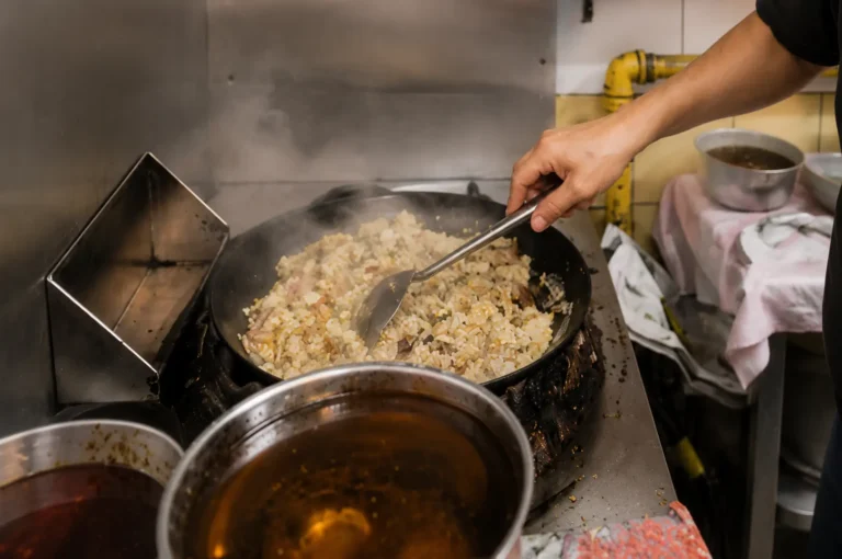 Chef stir-frying fried rice in a steaming wok