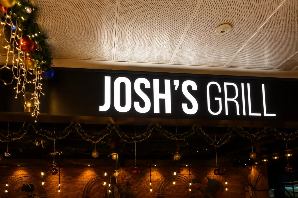 Josh's Grill restaurant illuminated sign with festive Christmas decorations and hanging ornaments