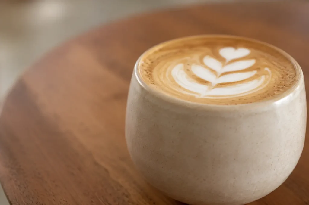Latte art in a ceramic cup on a wooden table at Apartment Coffee Singapore