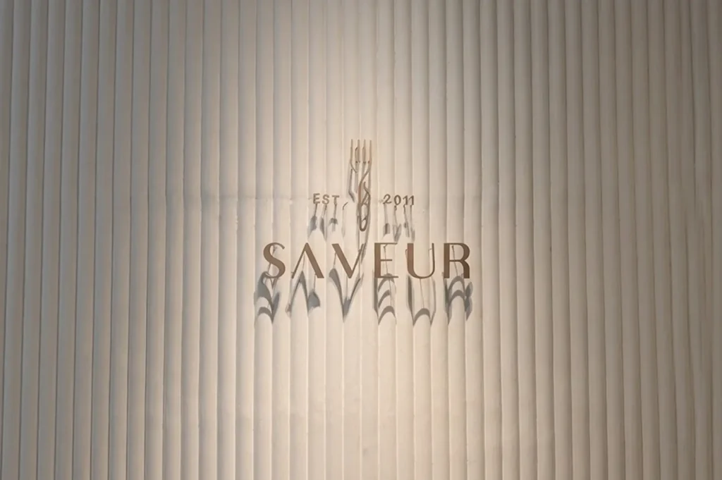 Saveur restaurant logo with establishment year 2011 on textured wall