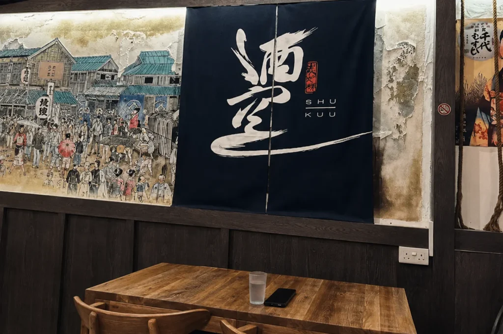 Shu Kuu izakaya interior showing dark blue noren curtain and vintage Japanese mural
