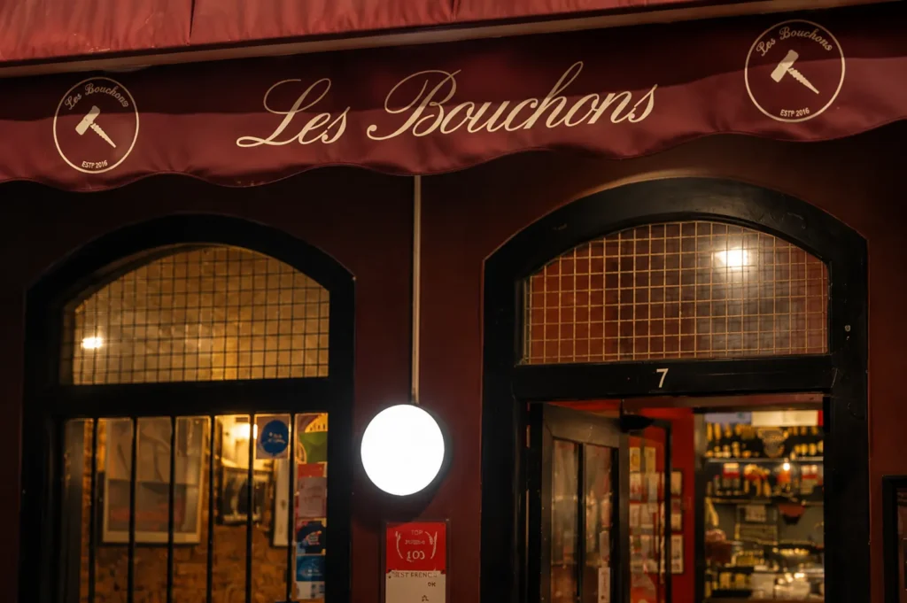 Les Bouchons French restaurant storefront with burgundy awning and arched windows