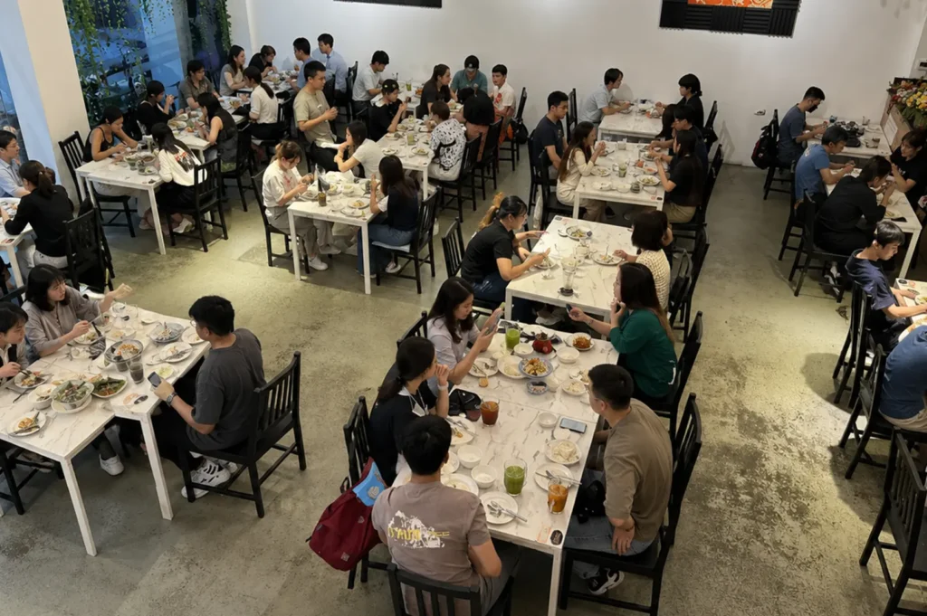 High-angle view of a busy dining room with customers eating at white marble tables