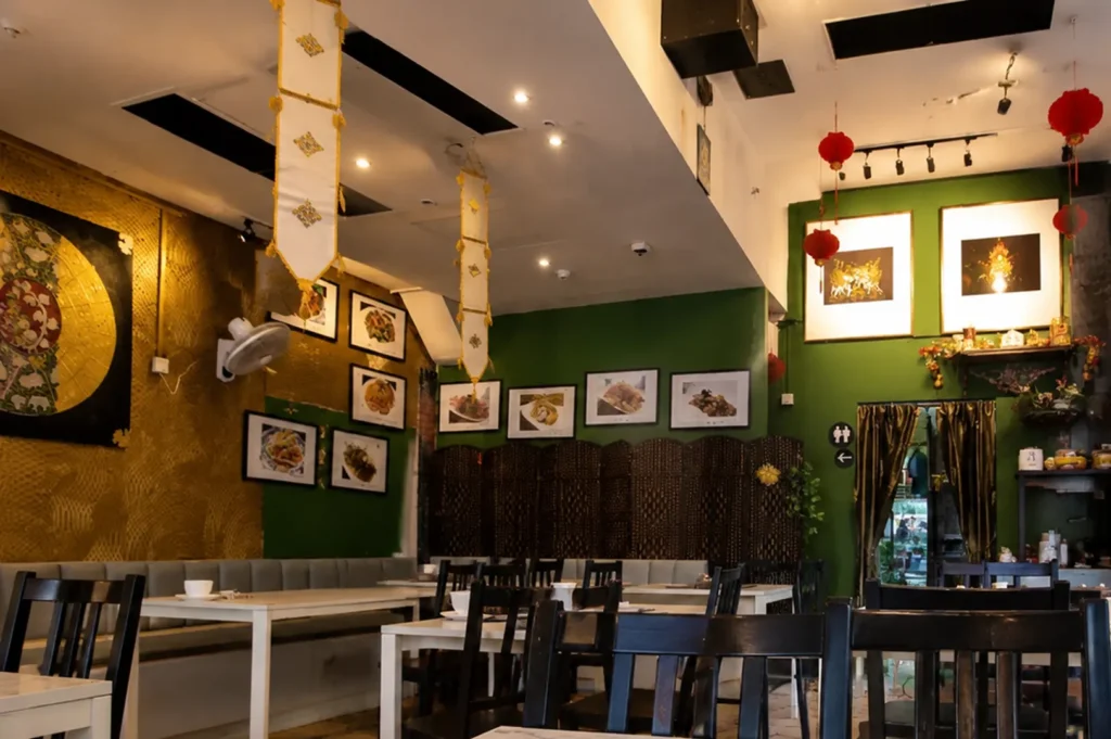 Ah Loy Thai restaurant interior featuring green walls, gold accents, red lanterns, and framed food photos