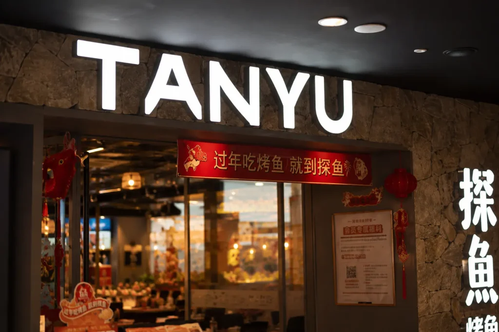 Tanyu restaurant storefront with illuminated sign, stone wall, and red Chinese lanterns