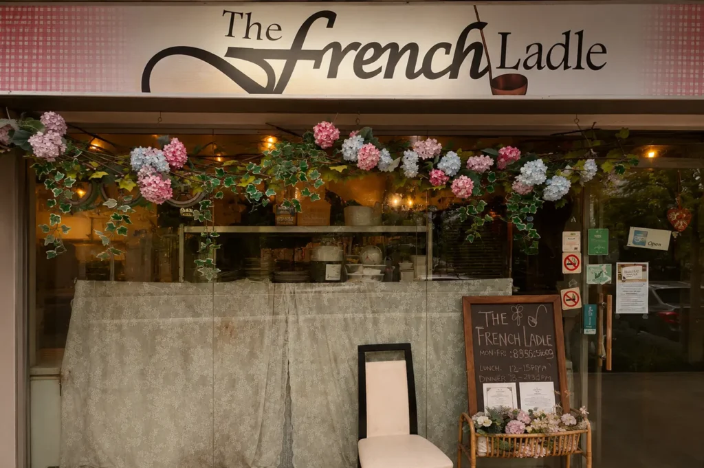 The French Ladle restaurant exterior featuring floral decorations and a chalkboard menu sign