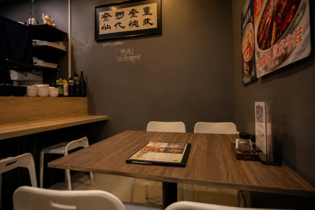 Cozy restaurant corner with wooden table, white chairs, and Chinese calligraphy on the wall