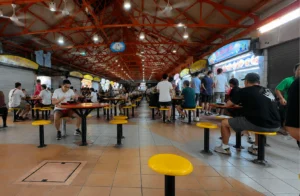 Bustling Singapore hawker centre filled with diners enjoying affordable local food.