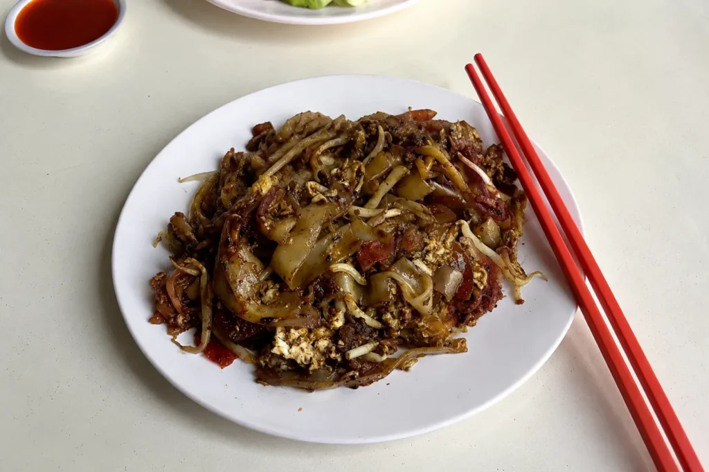 Plate of authentic Singapore char kway teow with bean sprouts and egg.