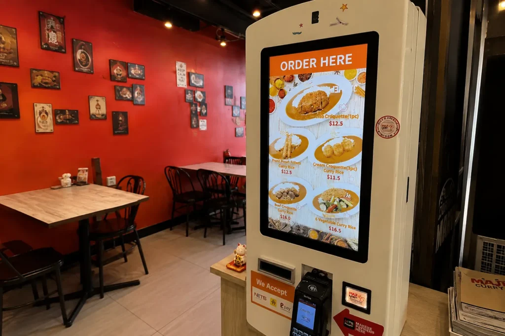 Maji Curry Singapore interior with red walls, dining tables, and self-ordering kiosk